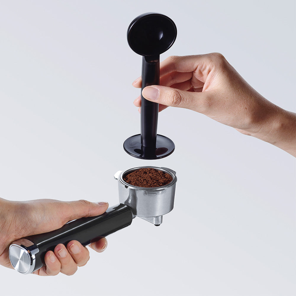 imagen prensando café molido con prensador en portafiltro cafetera