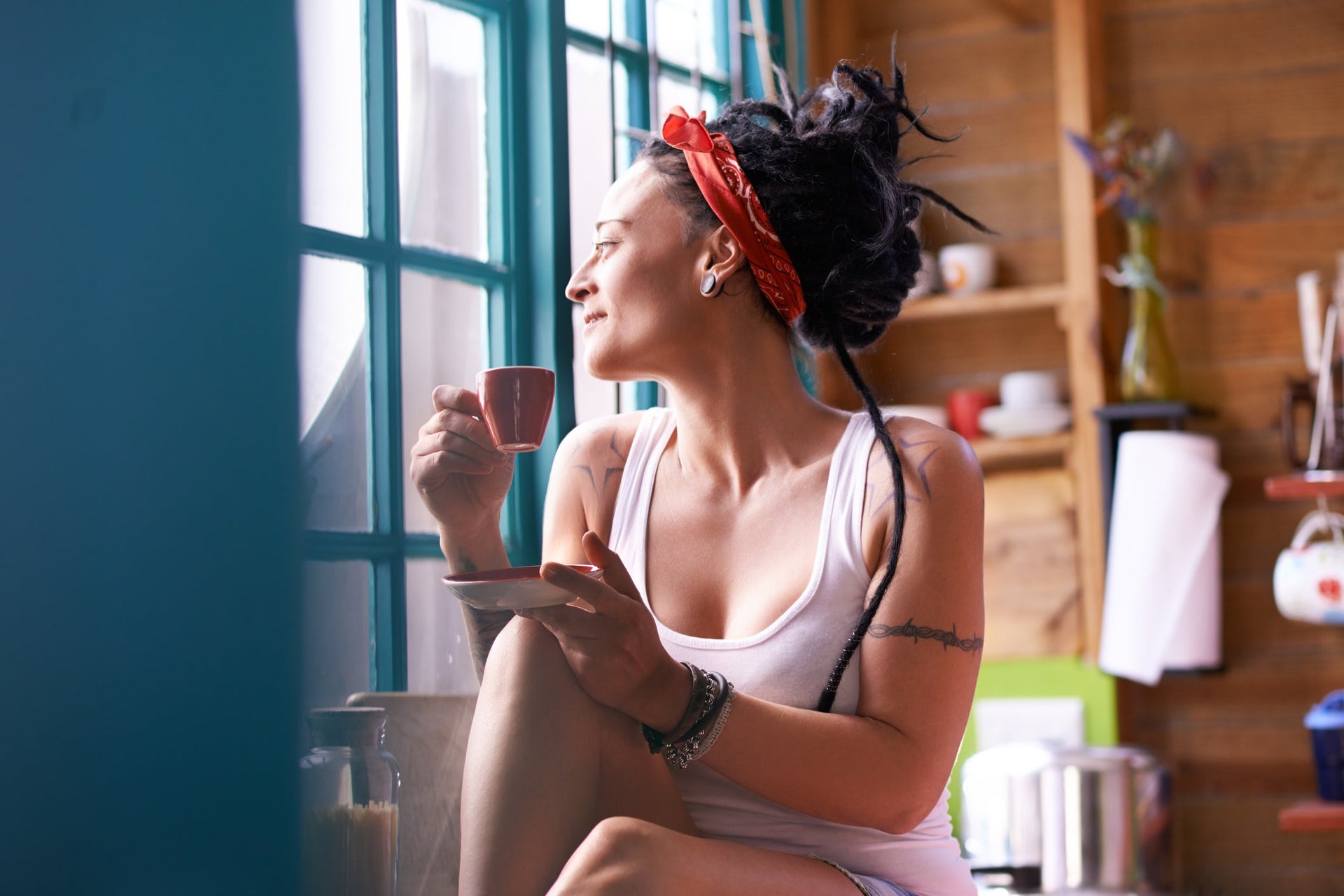 Mujer sosteniendo una taza de café mirando por la ventana